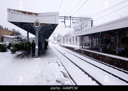 Pendler warten am Bahnhof Bahnsteig in North East London mit Schnee-Sturm Stockfoto