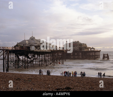 Menschen stehen am Strand vor Brighton der West Pier verfallen. Stockfoto