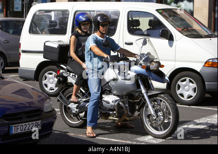 hispanic Mann auf silbernen BMW GS R1200 Motorrad mit weiblichen Pillion Passagier wartet an der Stop-Line tragen Helme im Verkehr sitzen Stockfoto