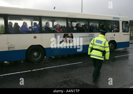 PSNI Polizist in Hallo Vis Jacke begleitet Ulster Bus voller Linfield Anhänger durch katholische republikanischen Gebiet von West Belfast Stockfoto