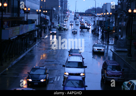 Autos fahren durch eine belebte Kreuzung an einem Regen und nassen Nacht auf der Randolph Street, Downtown Chicago, IL USA Stockfoto