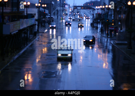 Autos fahren durch eine belebte Kreuzung an einem Regen und nassen Nacht auf der Randolph Street, Downtown Chicago, IL USA Stockfoto