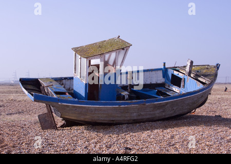 Seitlicher Blick auf eine verlassene Fischerboot am Kiesstrand bei Dungeness in Kent. Stockfoto