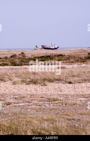 Verlassene Fischerboot in der Ferne auf den Kiesstrand bei Dungeness in Kent Stockfoto