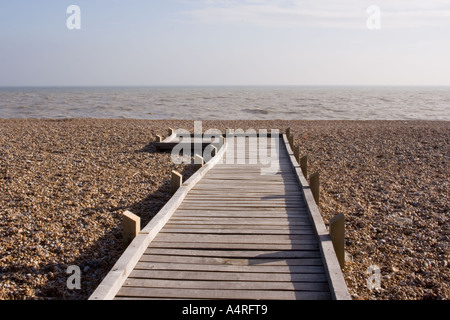 Ein Holzsteg führt über den Kiesstrand in Richtung Meer bei Dungeness horizontale Stockfoto