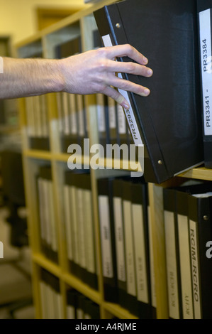 junge Studentin, die Recherche in den lokalen Aufzeichnungen Büro Lancashire zieht ein Buch aus dem Regal Stockfoto