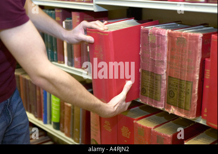 junge Studentin, die Recherche in den lokalen Aufzeichnungen Büro Lancashire zieht ein Buch aus dem Regal Stockfoto