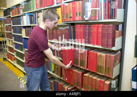 junge Studentin, die Recherche in den lokalen Aufzeichnungen Büro Lancashire zieht ein Buch aus dem Regal Stockfoto