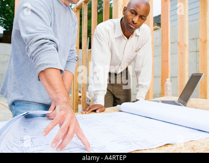 Zwei Männer betrachten Blaupausen auf Baustelle. Stockfoto