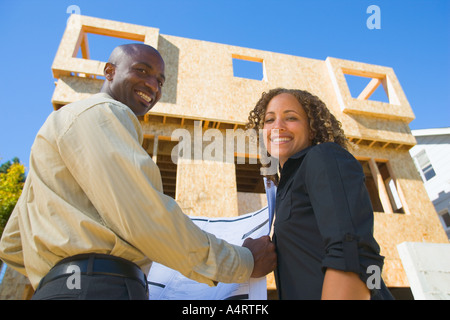 Porträt von lächelnden jungen Paar mit neuen Haus im Bau. Zweisamkeit zwei Menschen Frau Frau Frauen Holz hölzern jung Stockfoto