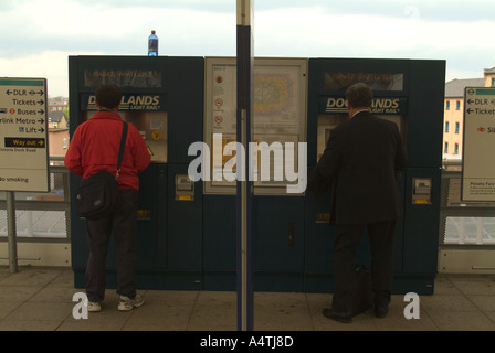 Reisende, die kaufen Bahntickets von Automaten am Bahnsteig Docklands London UK Stockfoto