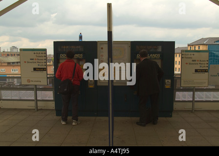 Reisende, die kaufen Bahntickets von Automaten am Bahnsteig Docklands London UK Stockfoto