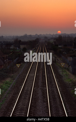 Bahn führt zu die untergehende Sonne am Horizont in Bradford Abbas Dorf Dorset county England UK Stockfoto