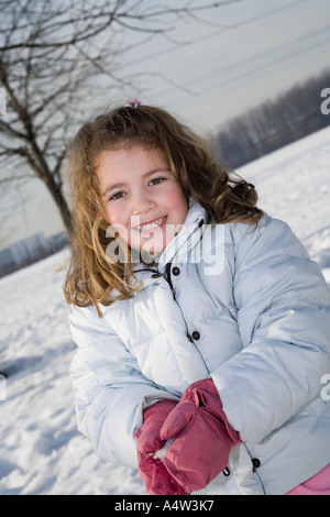 Kleines blondes Mädchen im Park bedeckt mit Schnee Stockfoto