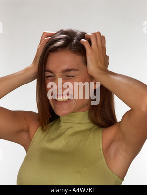 MÄDCHEN IM GRÜNEN OBEREN KNIFF GESICHT UND KOPF HOLDING Stockfoto