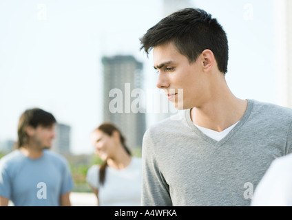 Junger Mann auf der Suche auf der Seite, junge Paar im Hintergrund Stockfoto