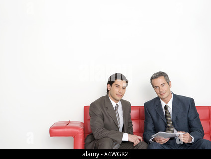 Zwei Geschäftsleute auf Couch sitzen, eine Holding-Dokument Stockfoto