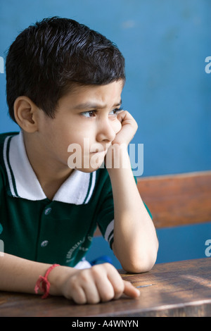 Kleiner Junge stützte sich auf Schreibtisch Stockfoto