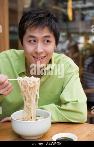 Junger Mann essen Nudeln Stockfoto
