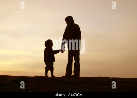 Silhouette von Mutter und Kind gegen Skyline auf Hügel im winter Stockfoto