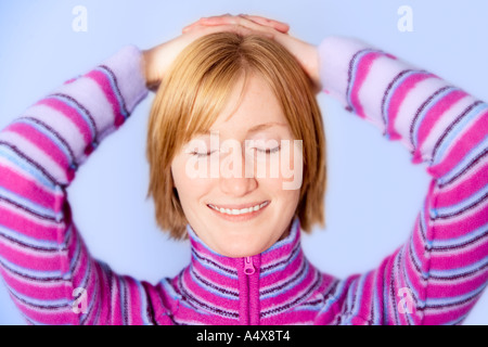 Junge Frau mit Hände hinter den Kopf, die Augen geschlossen, Lächeln, Nahaufnahme Stockfoto