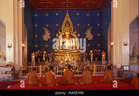 Mönche sitzen vor einem goldenen Buddha, Hilfe von den Thai-Tempel, Bodhgaya, Bihar, Indien Stockfoto