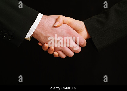 Männliche und weibliche Geschäftsleute Händeschütteln gegen einen schwarzen Hintergrund schließen sich Stockfoto