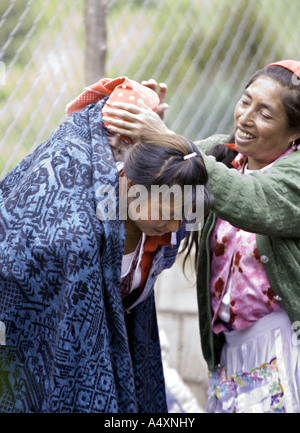 GUATEMALA CAPELLANILLA traditionell gekleidet Maya Quiche Großmutter hilft ihrer Tochter Stockfoto