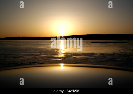 Sonnenuntergang über den zugefrorenen Fluss in New Brunswick Kanada Nordamerika mit Schwung des silbernen Autodach im Vordergrund Stockfoto