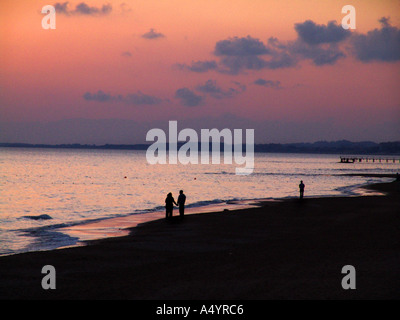 paar Spaziergänge am Strand in den Sonnenuntergang Paar Spaziert bin Strang in Den Raummotive hinein Stockfoto