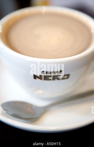 Volle Kaffeetasse mit Löffel und Caffe Nero Schriftzug Stockfoto