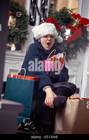 Weihnachts-Shopper reiben Wunde Füße müde Stockfoto