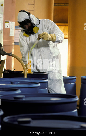 Arbeiter überprüfen Chemikalienlager Trommeln tragen schützende Tyvec Anzug und Gasmaske Stockfoto