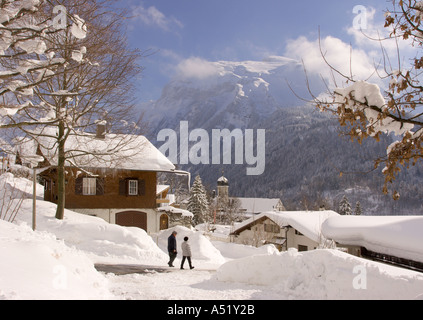 Paar gehen Sie Hang Road mit tiefem Schnee in der Sonne auf jeder Seite in Engelberg im Kanton Obwalden in der Zentralschweiz Stockfoto