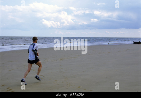 Mann läuft auf den Strand, Frinton-on-Sea, Essex, UK. Stockfoto