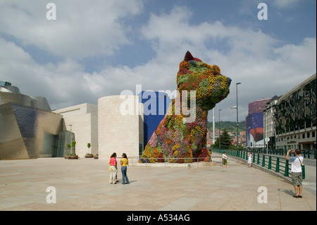 Touristen bewundern Jeff Koons Formschnitt Skulptur 'Welpen' außerhalb das Guggenheim Museum, Bilbao, nachdem seine Blumen bepflanzt sind. Stockfoto