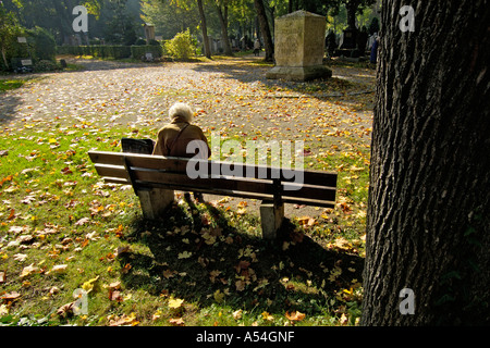 Alte Dame Frau auf Parkbank auf Osten Friedhof München Bayern Deutschland Stockfoto