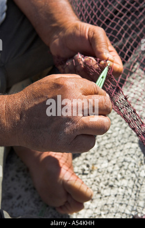Nahaufnahme von Fischer s Hände und Finger Reparatur Netze am Kai in Griechenland Stockfoto