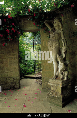 Klassische Statue auf Steinsockel neben offenen Metalltor in Wand und Blick auf Garten Pashley Manor in Sussex Stockfoto