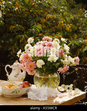 Still-Leben von rosa Dahlien und weißen Chrysanthemen in Glasvase auf Tisch im Garten Stockfoto