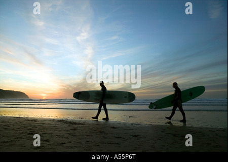 Zwei männliche Surfer Silhouette gegen den Sonnenuntergang Himmel am Strand von Perranporth an der Nordküste Cornish. Stockfoto