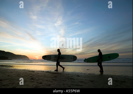 Zwei männliche Surfer Silhouette gegen den Sonnenuntergang Himmel am Strand von Perranporth an der Nordküste Cornish. Stockfoto