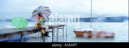 Deutschland, Sipplingen, Bodensee, Mutter und Kind sitzt an einem Anlegesteg im Regen Stockfoto