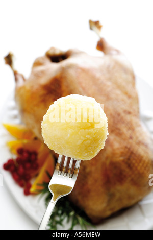 Kartoffelknödel auf Gabel, gebratene Gans im Hintergrund Stockfoto