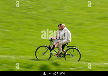 Paar Reiten Fahrrad in Wiese Stockfoto