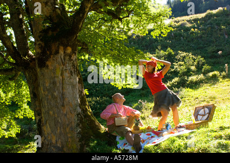 Paar beim Picknick unter Baum, Frau tanzt Stockfoto