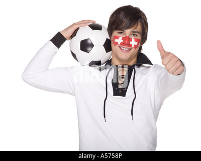 Junger Mann mit Schweizer Flagge auf Gesicht gemalt und Fußball auf den Schultern tragen Stockfoto