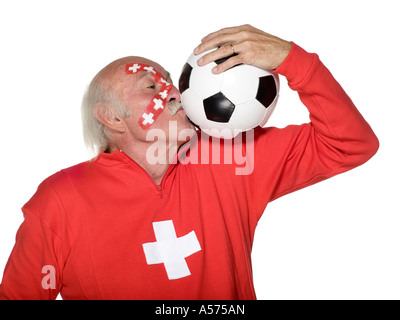 Ältere Menschen mit Schweizer Flagge gemalt auf Gesicht und küssen Fußball Stockfoto