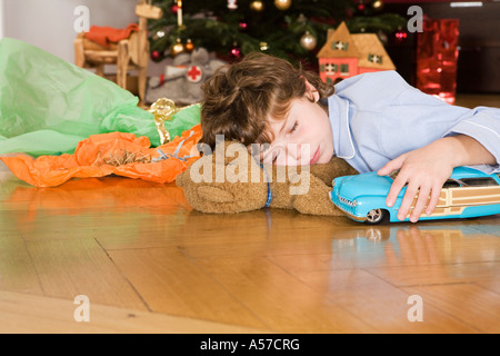 Jungen schlafen unter Weihnachtsbaum hält Spielzeugauto Stockfoto