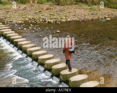 Frau zu Fuß über Beton Trittsteine über Roxby Beck Staithes North Yorkshire Stockfoto